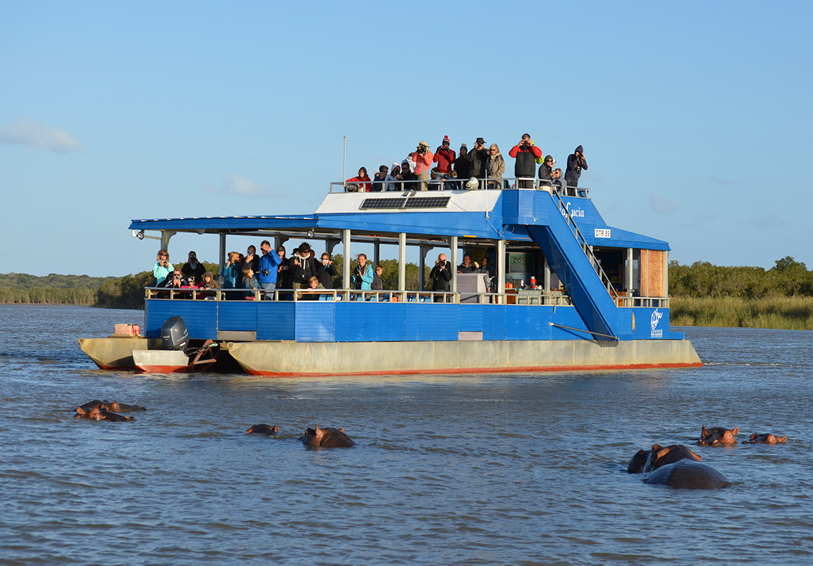 Mensen bekijken nijlpaarden op een boot tijdens een safari op de rivier in St. Lucia, Zuid-Afrika